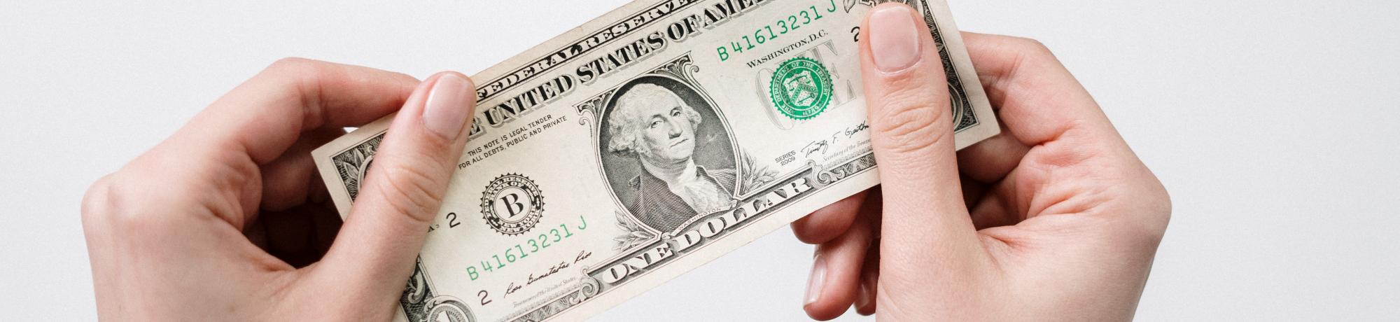 Set of hands holding a one dollar bill